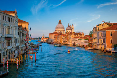 Buildings by river against sky