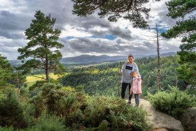 Mother and daughter standing on the edge of cliff in wicklow mountains, ireland