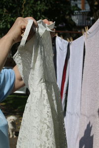 Cropped image of women holding dress while standing by clothesline in yard