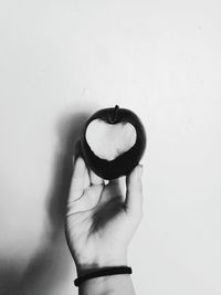 Midsection of woman holding heart shape against white background