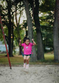 Cute girl sitting on swing at playground