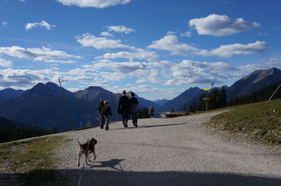 Man with dog walking on road against mountain range