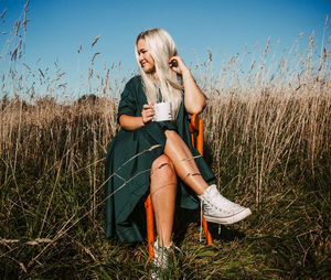 Full length of young woman sitting on field