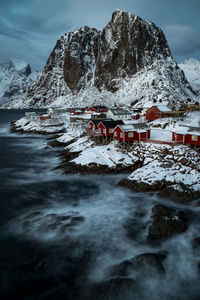 Aerial view of sea by town against mountain during winter