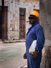 Side view of man standing against built structure