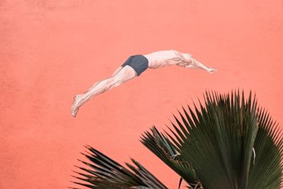 Midsection of man with palm tree against sky