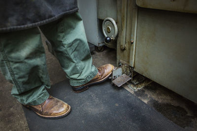 Low section of worker working on machinery at workshop