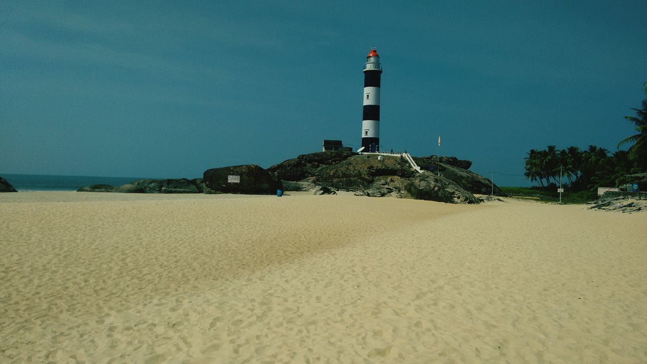 beach, sea, sand, guidance, lighthouse, clear sky, shore, built structure, architecture, building exterior, horizon over water, water, protection, copy space, direction, safety, sky, tranquility, tranquil scene, blue