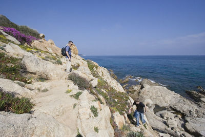 Men climbing mountain against clear sky