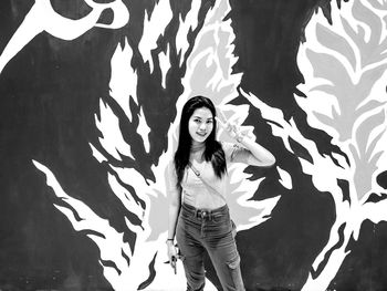 Portrait of young woman standing against wall