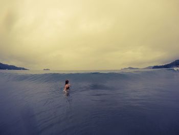 Man swimming in sea against sky