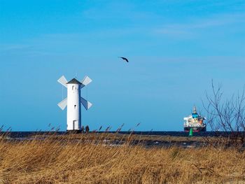 Lighthouse on field against sky