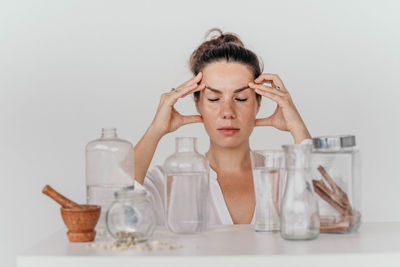 Portrait of young woman drinking bottles against white background