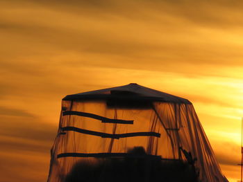 Tent against orange sky at sunset