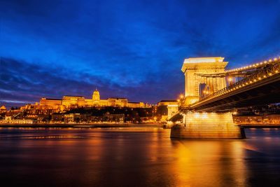 Illuminated bridge over river at night