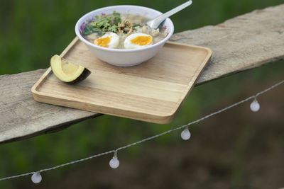 Porridge in a serving bowl with avocado on a wooden tray looks beautiful.