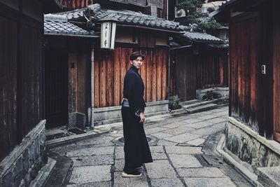 Portrait of woman standing against building