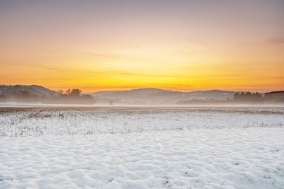 Scenic view of snowy landscape against sky during sunset