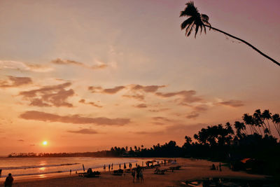 Silhouette palm trees on beach against sky during sunset