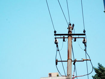 Low angle view of electricity pylon against clear blue sky