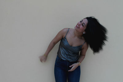 Happy woman tossing hair against wall