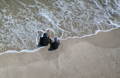 High angle view of carefree women sitting on shore at beach