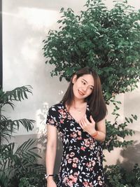 Beautiful young woman standing against plants