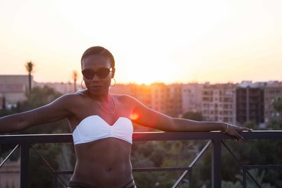 Woman wearing sunglasses against sky during sunset