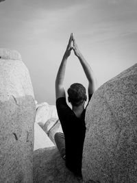 Rear view of boy on rock against sky
