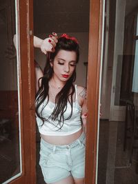 Portrait of young woman standing against wall