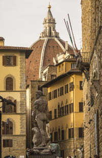 Low angle view of statue and duomo santa maria del fiore in city