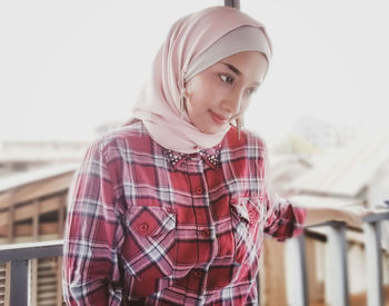 Portrait of smiling young woman standing against wall