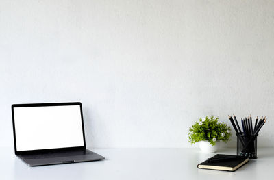 Potted plant on table against white wall