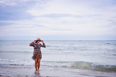 Full length of woman standing on beach against sky