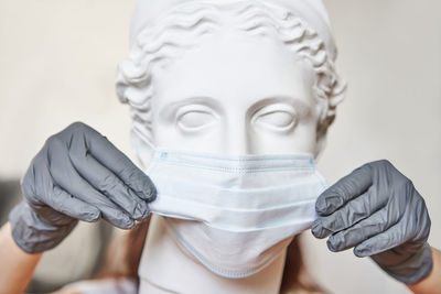 Close-up of human hand holding statue against white background