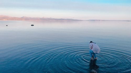 Rear view of man standing in sea against sky