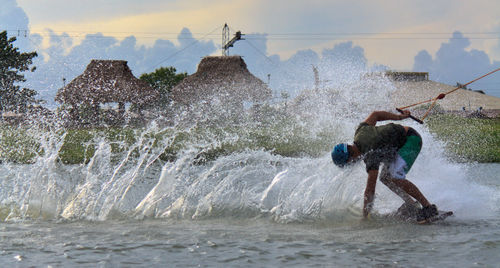 Man surfing in water against sky