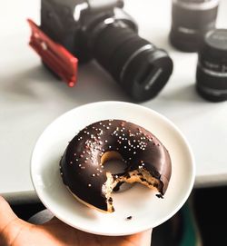 Close-up of hand holding donut in plate