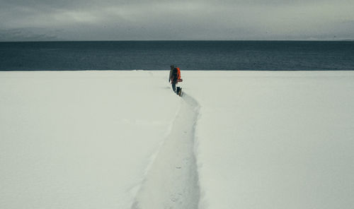 Rear view of woman walking on beach against sky