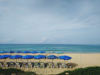 Chairs on beach against sky