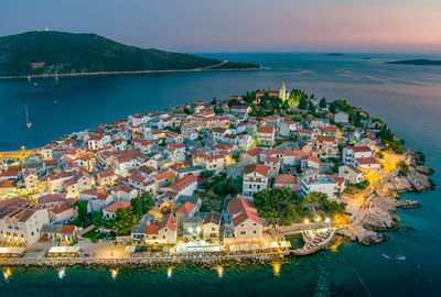 High angle view of townscape by sea against sky during sunset