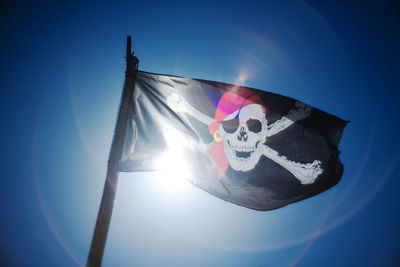 Low angle view of flag against clear blue sky