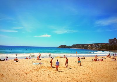 People on beach against blue sky