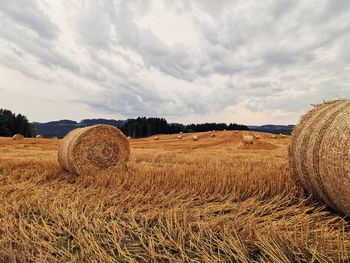 Hay bales on field against sky