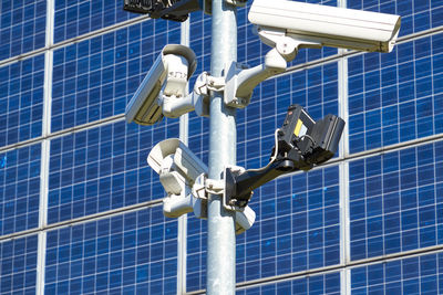 Low angle view of security cameras against solar panels