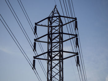 Low angle view of electricity pylon against blue sky