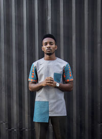 Portrait of young man standing against wall