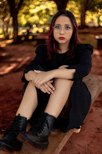 Portrait of teenager girl sitting on bench at park