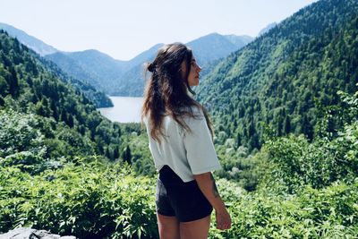 Woman standing by plants against mountains