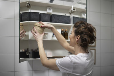 Woman putting basket in cupboard